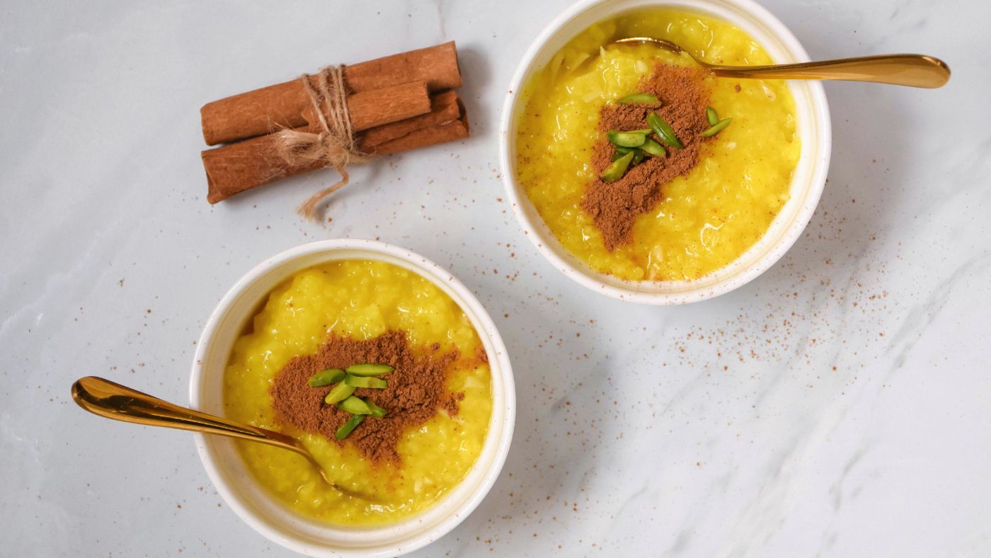 Two bowls of golden saffron rice pudding garnished with pistachios and cinnamon, traditional Ramadan Iftar dessert